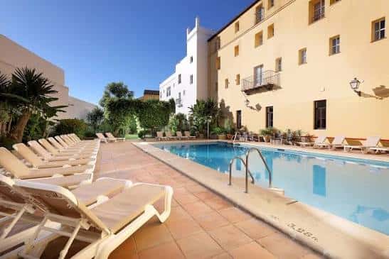 Piscina exterior con tumbonas y jardines del hotel