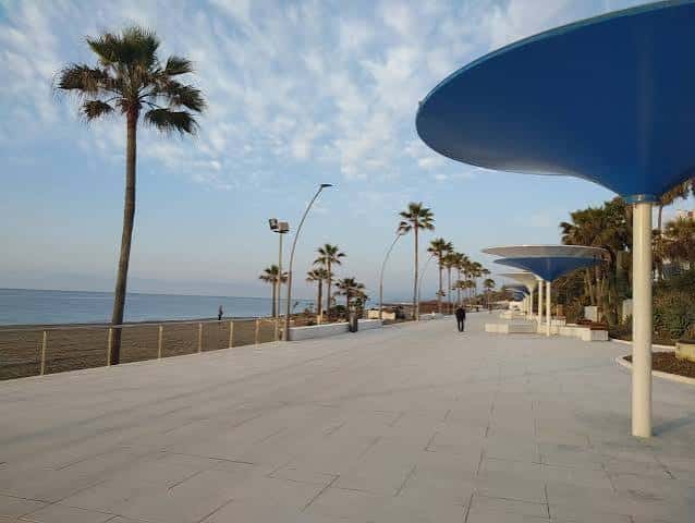 Paseo marítimo de Estepona con palmeras y estructuras azules frente al mar