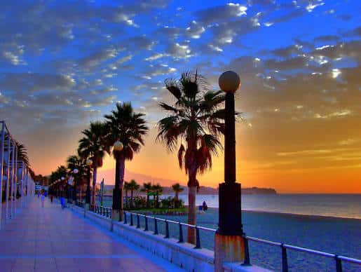 Atardecer en el paseo marítimo de Estepona con cielo colorido y siluetas de palmeras