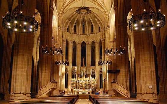 Vista del interior de la catedral iluminado, destacando el altar y los candelabros colgantes