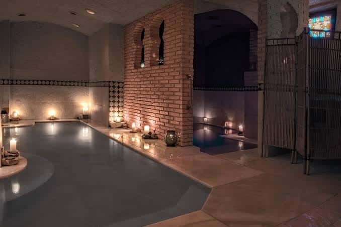 Interior del Hammam Almeraya con piscina iluminada por velas y arquitectura de ladrillo