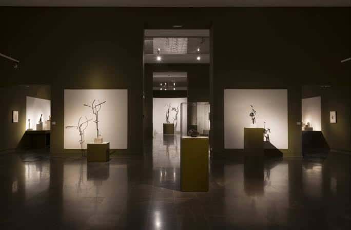 Sala de exposición con esculturas de Julio González iluminadas en ambiente oscuro