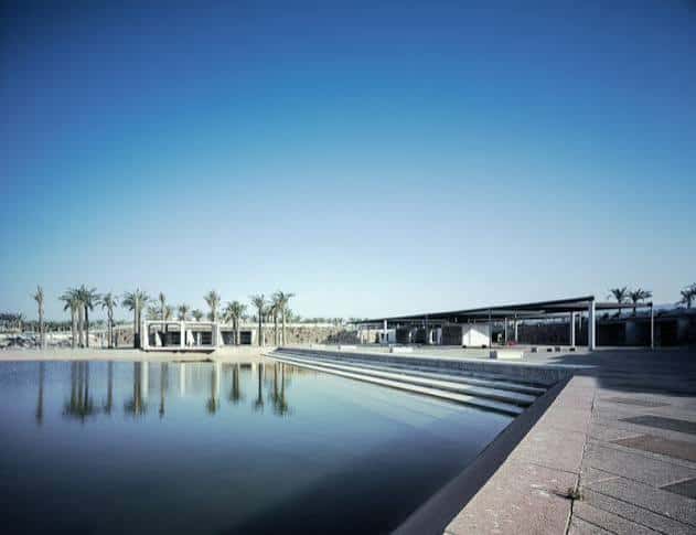Reflejo arquitectónico en el agua de la Plaza del Mar con palmeras y estructuras modernas