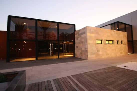 Vista exterior del Auditorio Infanta Leonor con fachada de vidrio y piedra al atardecer