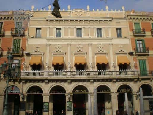Vista frontal de la fachada principal del Teatre Fortuny con sus balcones y toldos amarillos