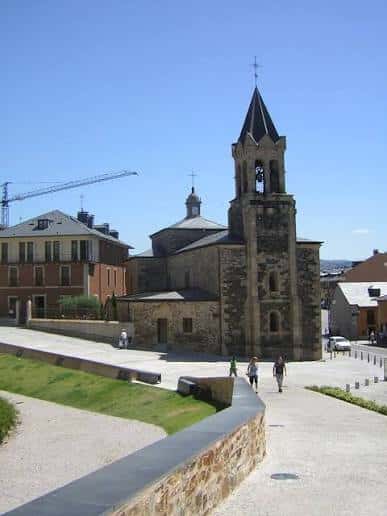 Vista exterior de la Iglesia de San Andrés con su torre campanario y fachada de piedra bajo un cielo despejado