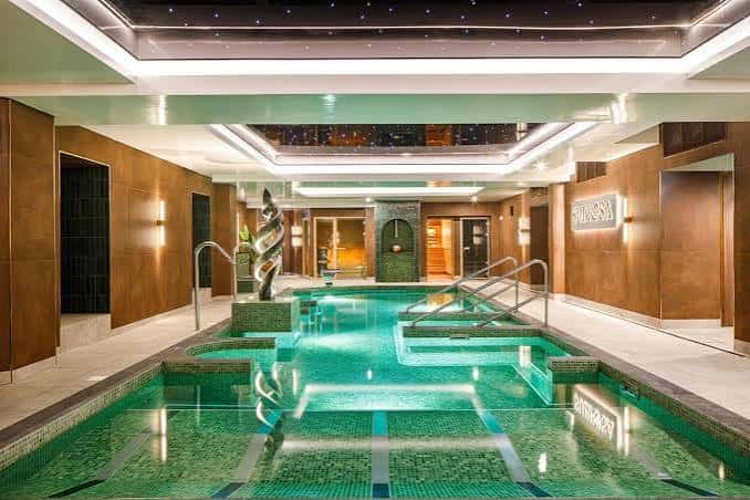Piscina interior del spa del hotel con iluminación ambiental y diseño moderno