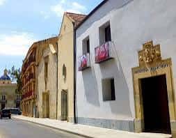 Vista exterior de la Biblioteca Pública María Moliner en Orihuela, mostrando su fachada blanca y la entrada principal con el escudo del Hospital Municipal