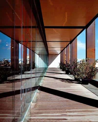 Pasillo interior con suelo de madera y paredes de cristal del edificio Metro