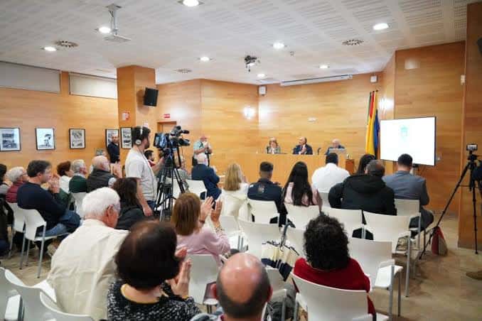 Interior del auditorio durante un evento con público y panel de ponentes