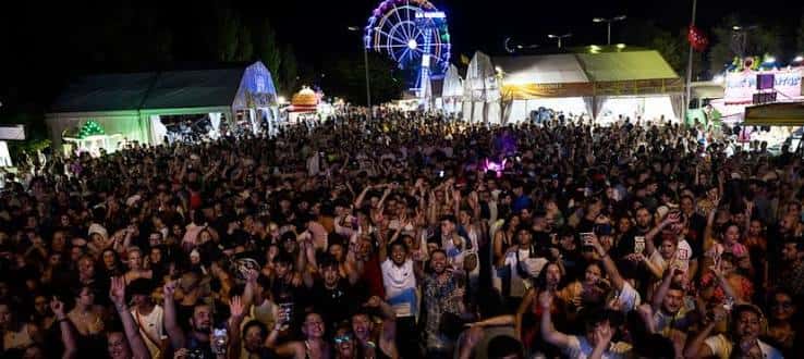 Multitud de asistentes en el recinto ferial con noria iluminada al fondo