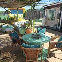 Terraza exterior con mesas y sillas bajo pérgola, ideal para eventos al aire libre