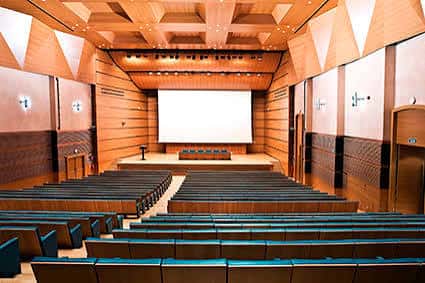 Sala de conferencias con pantalla proyectada y disposición en anfiteatro