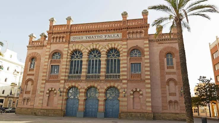 Vista exterior del teatro con palmera y entorno urbano en Cádiz