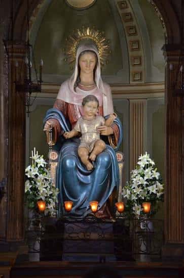 Estatua de la Virgen del Roser con el Niño Jesús en el altar