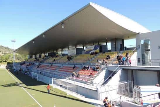 Fachada moderna de las gradas del estadio con techo inclinado y espectadores