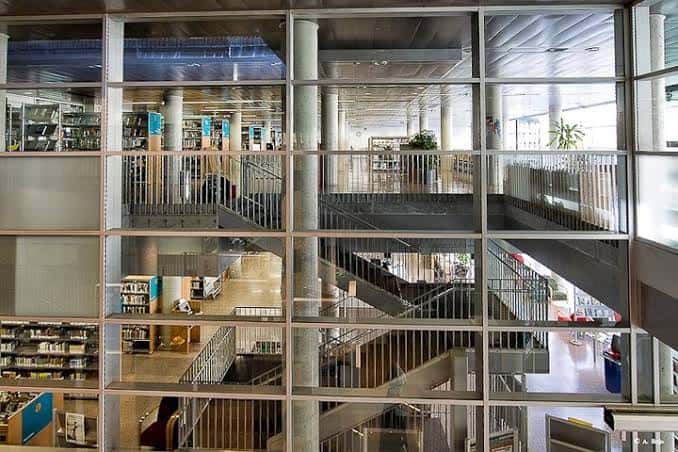 Interior de la biblioteca mostrando múltiples niveles, escaleras y estanterías de libros