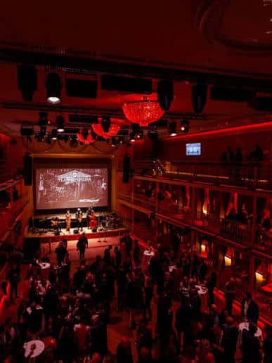 Interior del auditorio durante un evento con escenario iluminado y público reunido