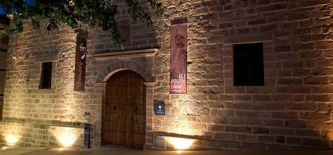 Detalle de la entrada principal de El Pósito con iluminación cálida y banderolas decorativas