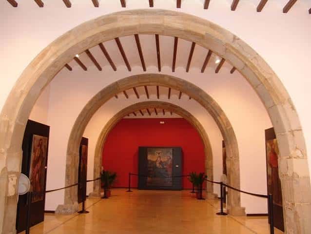 Interior de la Lonja Medieval con arcos de piedra y exposición de arte