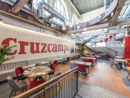 Interior del espacio de eventos con decoración industrial y mesas dispuestas para celebración