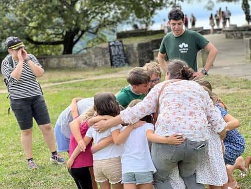Grupo de niños y adultos participando en una actividad grupal en el parque