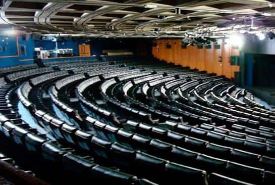 Vista panorámica del auditorio con butacas curvas y escenario iluminado