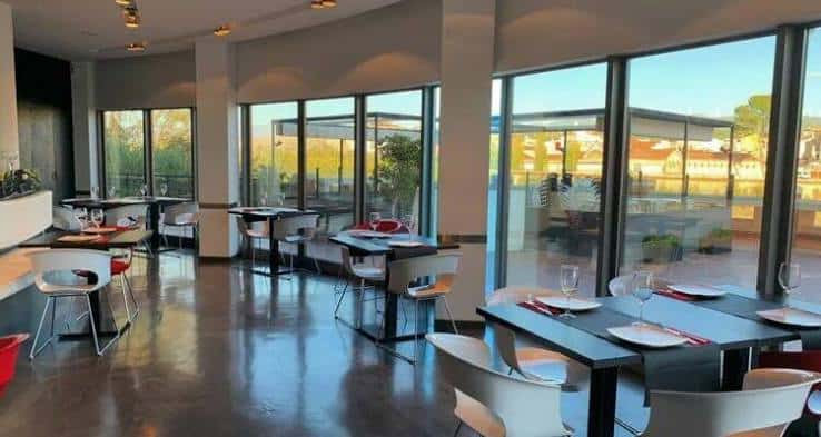 Interior moderno del restaurante Xapla con mesas dispuestas y grandes ventanales que dan a la terraza