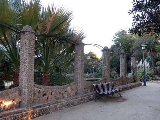 Paseo con bancos y columnas de piedra junto a palmeras