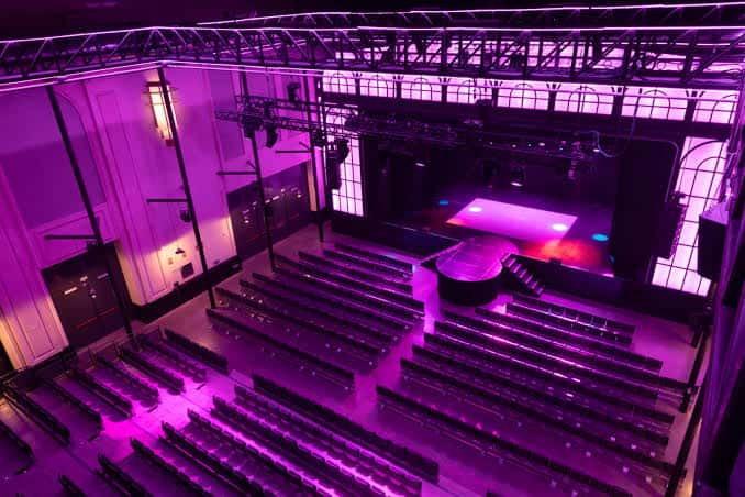 Vista panorámica del interior del Gran Teatro CaixaBank Príncipe Pío con iluminación púrpura y escenario listo para eventos