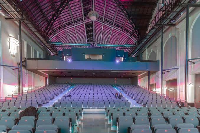 Espacio amplio del teatro con techos altos, balcones y disposición modular para conferencias o espectáculos