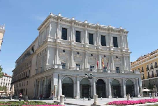 Vista exterior del Teatro Real desde la plaza con flores en primer plano