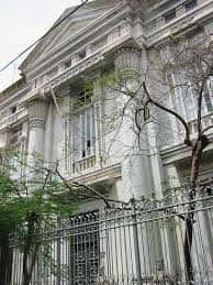 Vista lateral del edificio con árboles y reja frontal