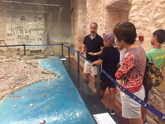 Grupo de turistas escuchando una explicación sobre un mapa histórico en un museo