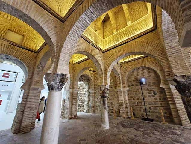 Interior iluminado de la mezquita con arcos de herradura y techos decorados