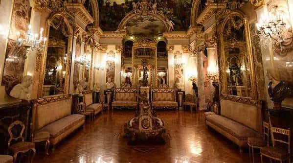 Interior del salón principal del Museo Cerralbo con sofás tapizados, espejos ornamentados, candelabros y suelo de madera pulida