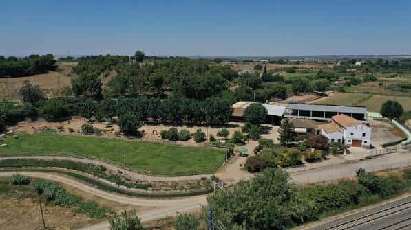 Vista aérea de la Granja Pifarré con sus edificios y zonas verdes bajo un cielo despejado