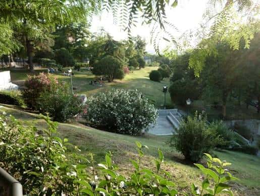 Paisaje verde de los jardines con senderos y zonas de descanso bajo la luz del atardecer