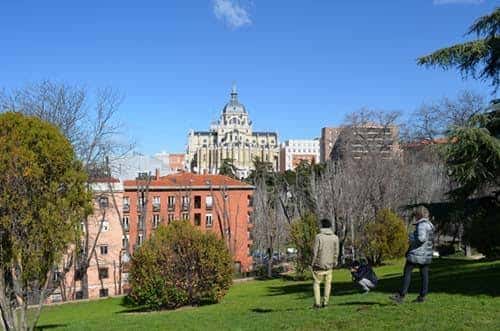 Grupo de personas disfrutando de la vista desde los jardines con el Palacio de Cibeles al fondo