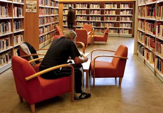 Zona de lectura interior con sillones rojos y estanterías de libros