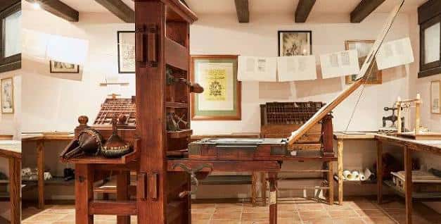 Interior de la Sociedad Cervantina mostrando una imprenta antigua y elementos culturales en exhibición