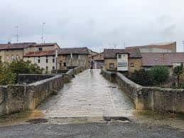 Puente de piedra en el concejo de Armiñón con edificios tradicionales al fondo