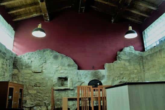 Interior del Centro Social de Manzanos mostrando paredes de piedra y techo de vigas de madera