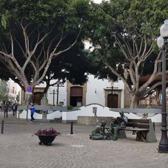 Plaza de San Gregorio con árboles frondosos, bancos y esculturas en primer plano