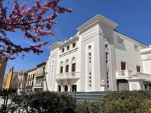 Fachada renovada del Casino de Rubí con flores de cerezo en primer plano