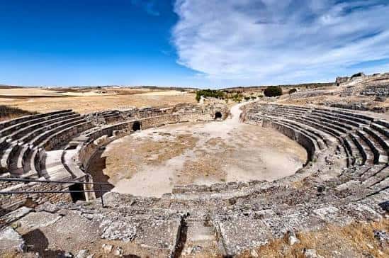 Vista panorámica del teatro romano de Segóbriga con gradas semicirculares y paisaje árido al fondo