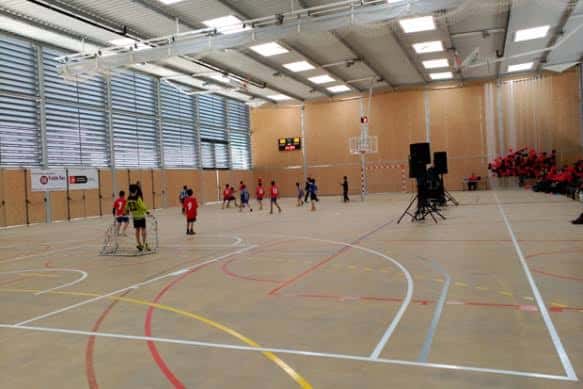 Actividad deportiva en el interior del pavelló con niños jugando y decoración floral