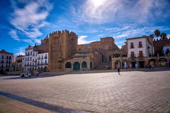 Plaza Mayor de Cáceres con torre medieval y cielo azul despejado