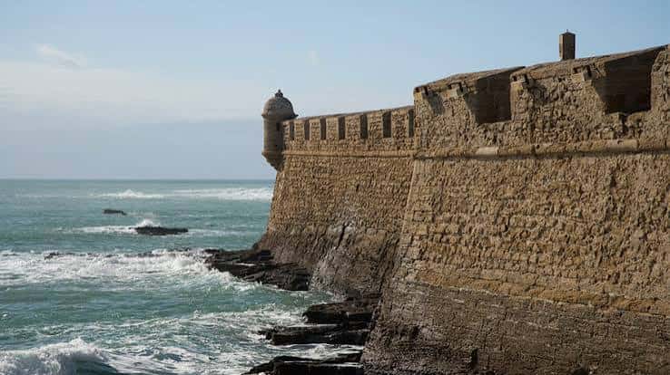 Detalle de la muralla costera del castillo con el mar rompiendo contra las rocas
