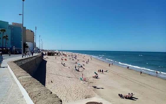 Vista panorámica de la playa de Cádiz con el paseo marítimo y edificios al fondo